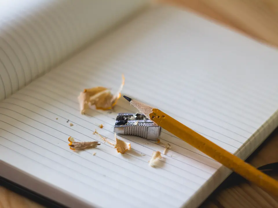 Açık çizgili defter üzerinde kalem ve kalemtıraş talaşı